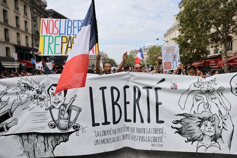 Des manifestants brandissent une banderole Liberté sous le drapeau français